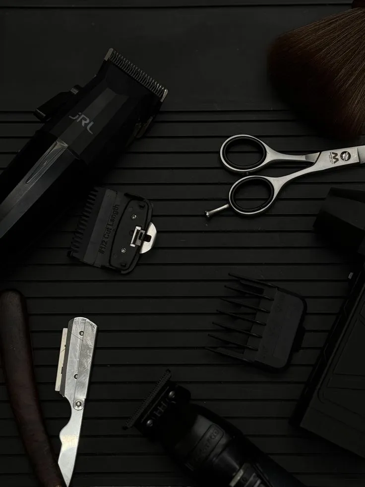 Sélection d'outils de barbier disposés avec soin sur un plateau noir